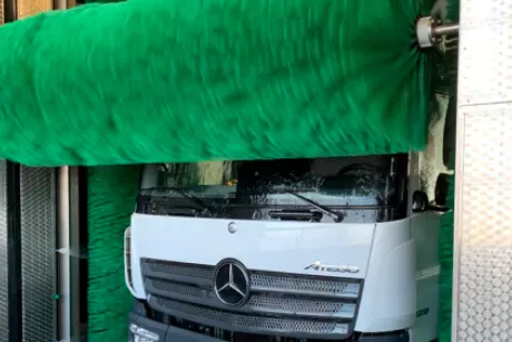 Rotierende Dachbürste einer DiBO-LKW-Waschanlage, Typ Berlin, die beim Waschen über die Front eines Mercedes-LKW rollt.
