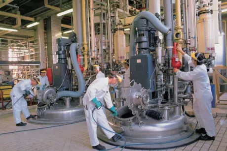3 personen in witte beschermkledij reinigen met spuitlansen RVS tanken voor opslag van chemie.
